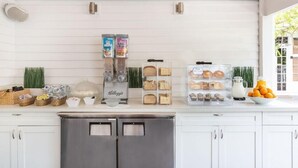 A kitchen with white cabinets, a stainless steel refrigerator, and various food items displayed on the counter. - Nyah Key West Adult Only (Key West)