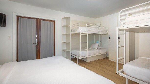 A room with bunk beds, a single bed, a door with curtains, and a ceiling light fixture. - Nyah Key West Adult Only (Key West)