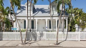 A white colonial-style house with a picket fence, palm trees, and a clear blue sky. - Nyah Key West Adult Only (Key West)