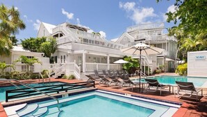 A pool area with lounge chairs and a pool, surrounded by a white building with multiple balconies. - Nyah Key West Adult Only (Key West)