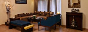 A living room with a sofa, armchairs, a coffee table, a side table, a lamp, a decorative vase, and a fireplace. - La Sunila Suites (Arpora)