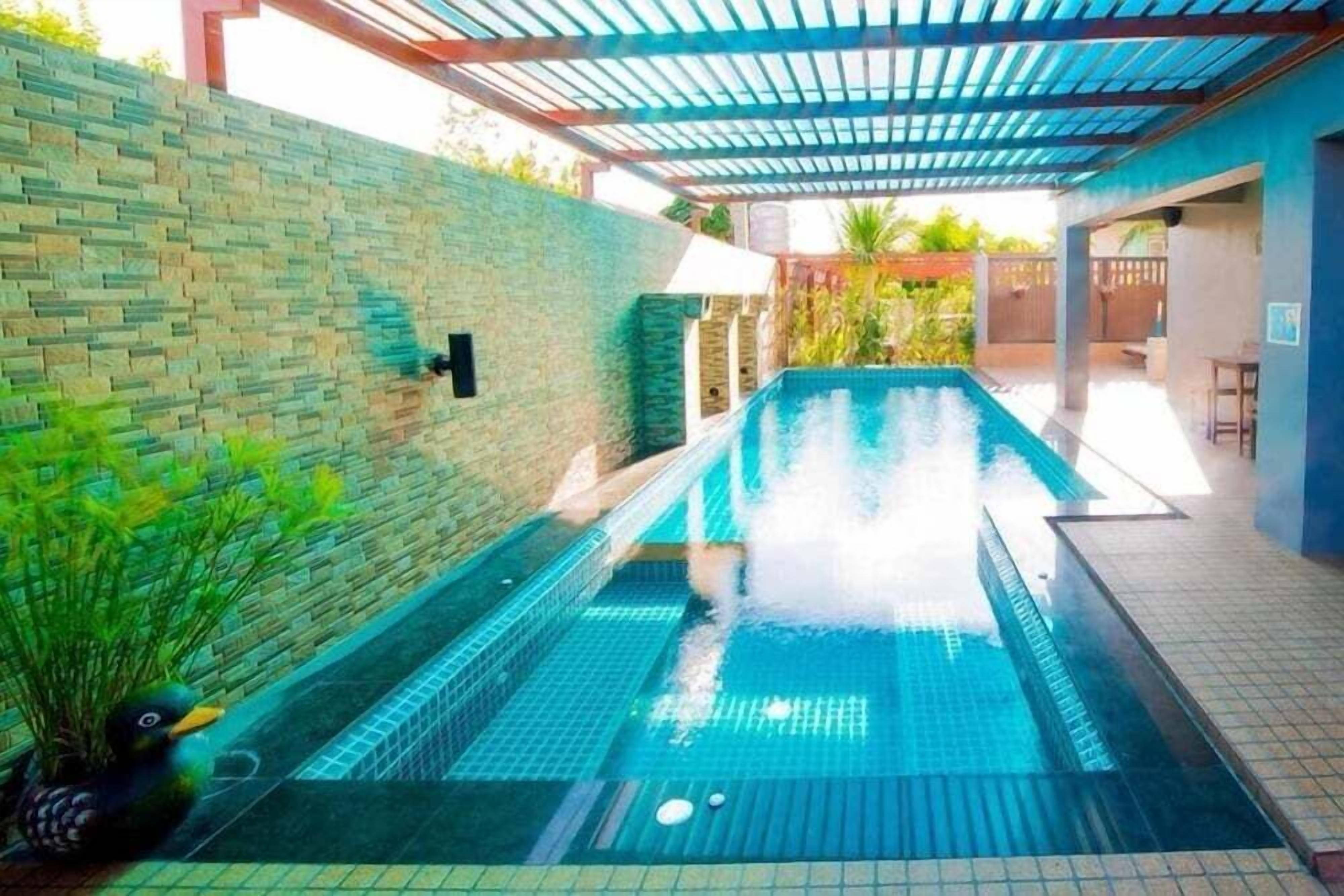 Ein Pool mit einer Springbrunnenanlage, umgeben von einer Ziegelmauer und einer überdachten Terrasse.