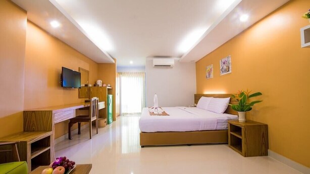 Ein Hotelzimmer mit Bett, Nachttisch, Fernseher, Schreibtisch, Stuhl und einer Obstplatte.