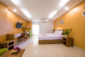 A hotel room with a bed, bedside table, TV, desk, chair, and a fruit plate. - Huahin Goodview Hotel (Hua Hin)