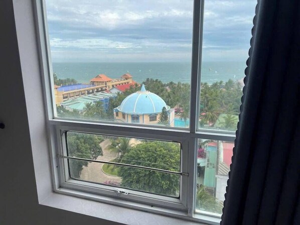 Blick aus einem Fenster auf eine Küstenlandschaft mit Gebäuden und einer Kuppelkonstruktion.