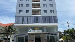 A multi-story hotel with a modern facade, balconies on each floor, and a storefront labeled "HOTEL MUI NE BOUTIQUE". - Nam Hai Hotel (Phan Thiet)
