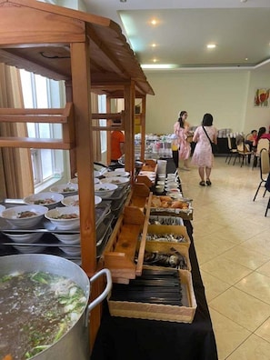 Montaje de bufé con varias estaciones de servicio, incluyendo fuentes de comida y utensilios.