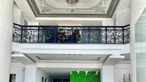 A spacious lobby with a high ceiling, decorative ceiling, and a balcony with ornate railings. - Nam Hai Hotel (Phan Thiet)