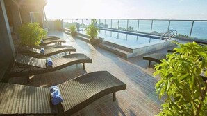 A rooftop terrace with sun loungers and a pool, overlooking a body of water. - Nam Hai Hotel (Phan Thiet)