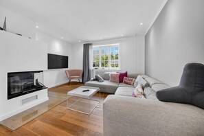 A modern living room with a flat-screen TV, a sofa, a chair, and a coffee table. - Hüs lepen Will - Stylish vacation home for 4 people with sauna, garden and (Hörnum (Sylt))