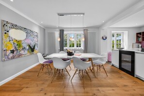 A modern kitchen with a dining area, wooden flooring, and a large abstract painting on the wall. - Hüs lepen Will - Elegant vacation home for 4 with a sauna, garden, and (Hörnum (Sylt))