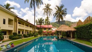 Un hôtel doté d’une piscine, de palmiers et avec une montagne en toile de fond.