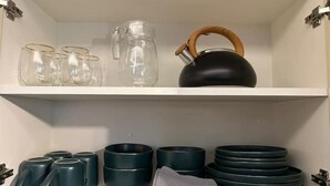 A kitchen shelf with glassware, a kettle, and stacked bowls. - Brand new apartment with private jacuzzi. (Cusco)