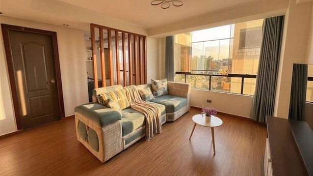 A living room with a sofa, a small round table, and a view of the outside through large windows. - Brand new apartment with private jacuzzi. (Cusco)