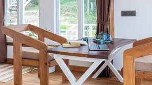 A modern dining area with wooden furniture, a laptop, and a teapot on a table.