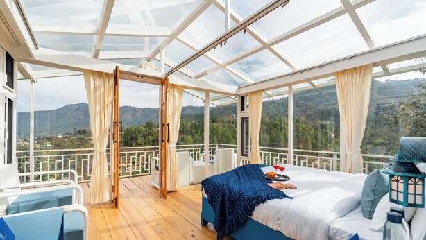 A room with a bed, a desk, and a view of the mountains.