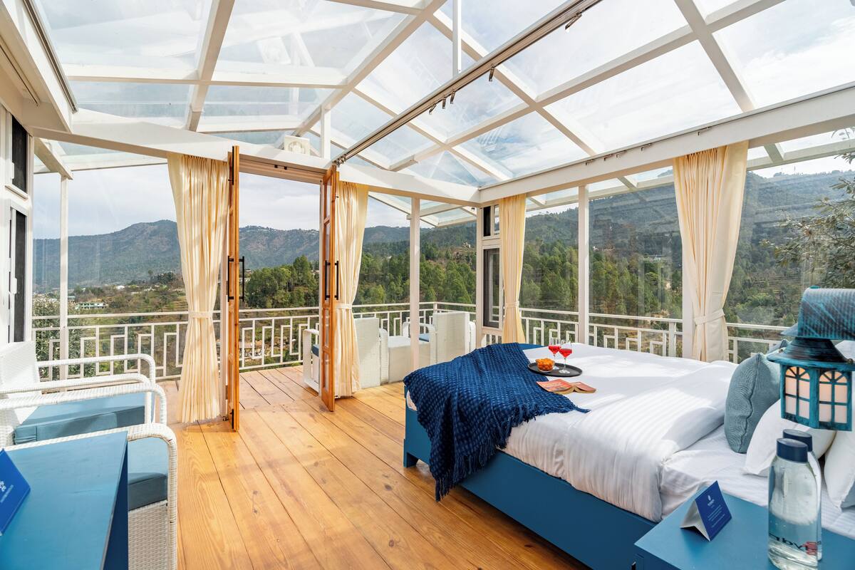 A room with a bed, a desk, and a view of the mountains.