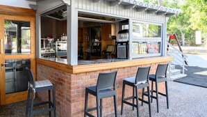 An outdoor bar area with a brick counter, two bar stools, and a grill.