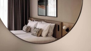 A modern hotel room with a large bed, two pillows, a headboard, and a wall-mounted artwork. - Strand Suites By Neu Collective (Gzira)