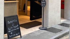 A building entrance with a sign offering sandwiches and soft drinks. - Strand Suites By Neu Collective (Gzira)