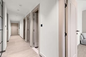 A hallway with multiple doors, a light-colored floor, and a chair in the corner. - Murjan 2802 (Dubai)
