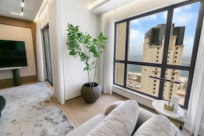 A modern living room with a large window, a flat-screen TV, a potted plant, and a sofa. - Murjan 2802 (Dubai)