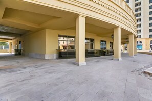 A spacious outdoor area with a yellow building featuring a curved balcony and a glass entrance. - Murjan 2802 (Dubai)