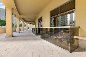 A covered outdoor area with a tiled floor, glass railings, and outdoor seating. - Sadaf 1507 (Dubai)