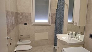 Ett modernt badrum med toalett, bidé och tvättmaskin.