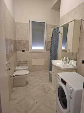 A modern bathroom with a toilet, bidet, and washing machine. - EriceIn apartments 800 mt from the beach Trapani (Casa Santa)