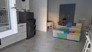 Ett modernt kök med ett kylskåp, en matplats med en färgglad soffa och ett litet bord.