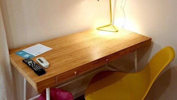 A wooden desk with a yellow chair, a lamp, and a trash bin. - B B Palazzo Zappala (Catania)