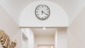 A hallway with a wooden floor, a clock on the wall, and a door at the end. - B B Palazzo Zappala (Catania)