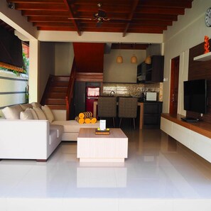 A modern living room with a sofa, a coffee table, and a TV. - Juada Garden (Seminyak)