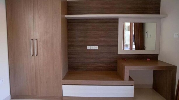 A bedroom with a wardrobe, a vanity with a mirror, and a built-in shelf. - Juada Garden (Seminyak)
