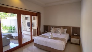 A modern bedroom with a large bed, a sliding glass door to a balcony, and a clean, minimalist design. - Juada Garden (Seminyak)