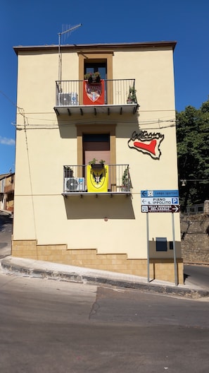 A building with a balcony, a sign indicating a sports field, and a World Heritage sign.