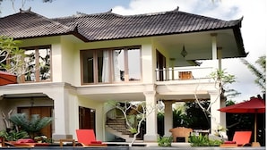 A two-story house with a swimming pool, a staircase, and a balcony.