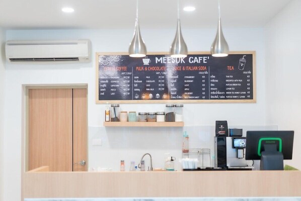 Una cafetería con un cartel que anuncia café, leche y chocolate, zumo y refrescos italianos, y té.