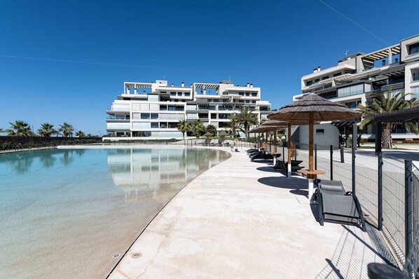 Ein modernes Hotel mit Schwimmbad, Liegestühlen und Sonnenschirmen.