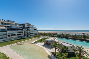 Ein modernes Hotel mit mehreren Etagen, einem Pool und Blick auf den Strand.