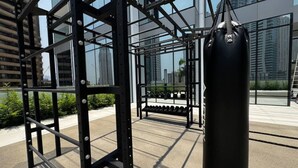 Area fitness con sacco da boxe, rastrelliera per pesi e manubri.