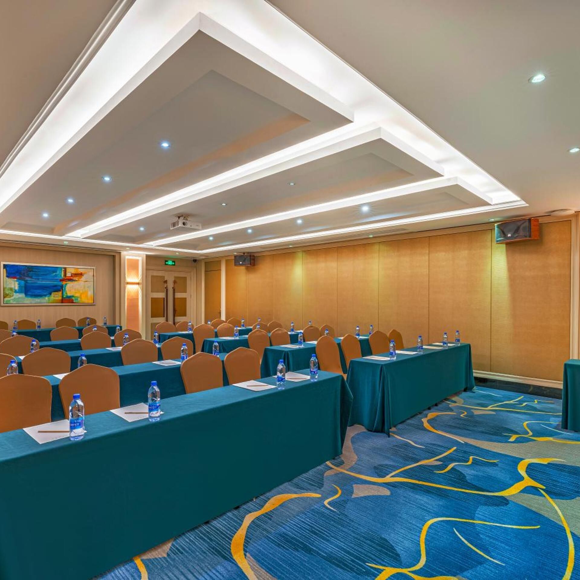 A conference room with tables, chairs, and a carpeted floor.