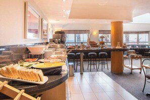Zona de bufé con diferentes opciones de comida y un área de estar con sillas.