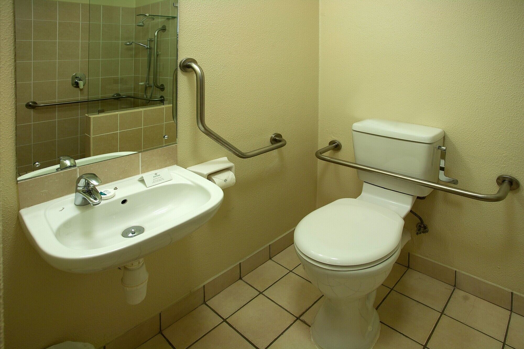 A bathroom with a white sink, toilet, and grab bars.