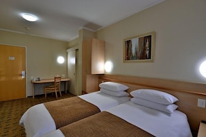 Habitación de hotel con dos camas, un escritorio y una silla.