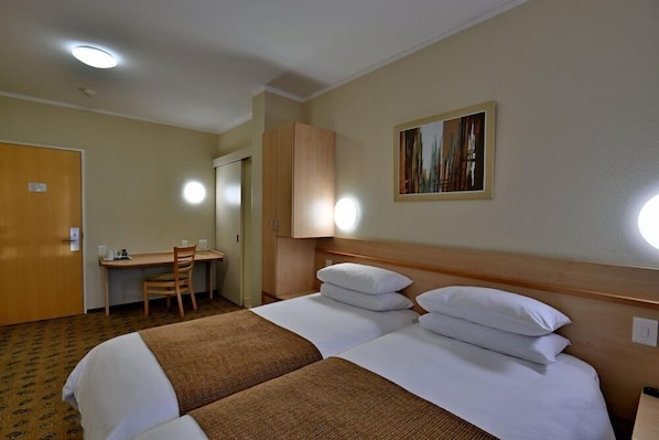 Habitación de hotel con dos camas, un escritorio y una silla.