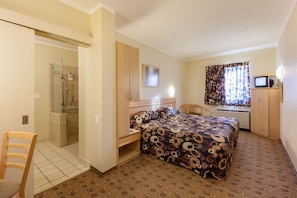 Habitación de hotel con ducha, cama, escritorio, silla y televisor.
