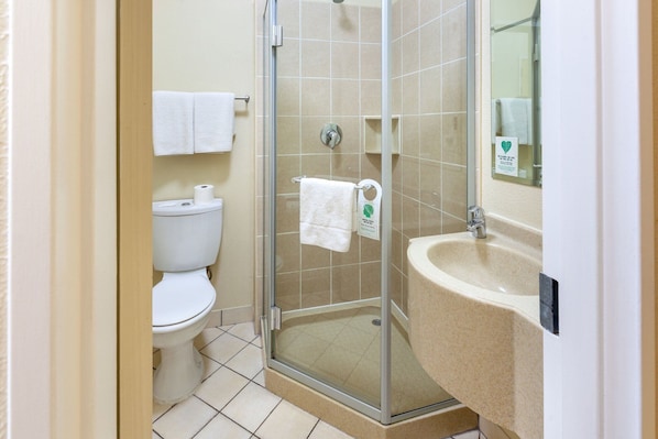 Un baño con inodoro, cabina de ducha de vidrio y lavamanos.
