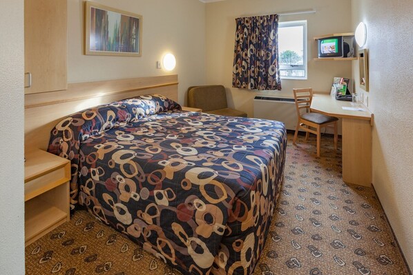 A hotel room with a bed, a desk, a chair, a television, and a window with curtains. - Road Lodge Gqeberha Airport (Gqeberha)